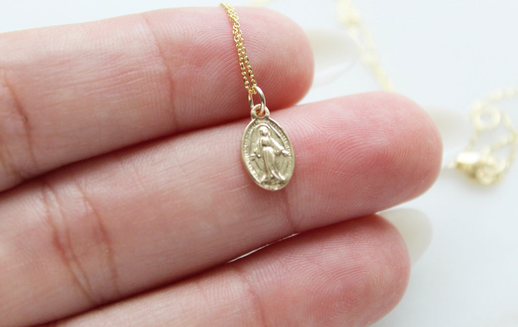 Handmade miraculous medal necklace in 14K Gold. Handmade Miraculous Medal is 1/2"x1/4". Chain is 14K Gold & dainty. This is a traditional miraculous medal with the Marian image on the front and Marian cross & 12 stars on the back.