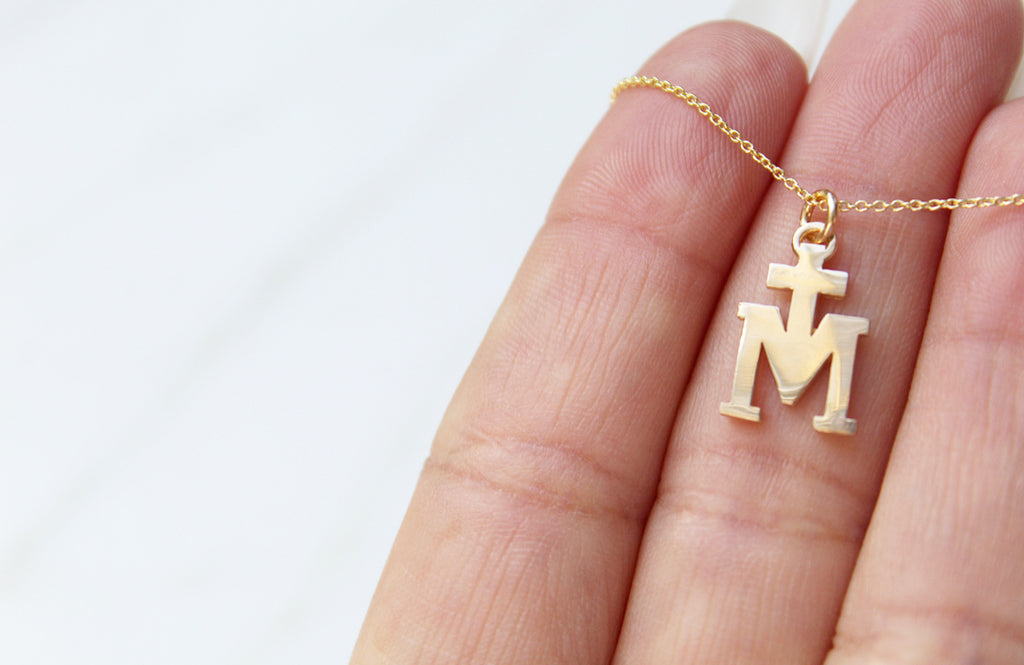 14K Gold Marian Cross necklace. Its a Cross Above the letter "m". The Marian Cross does not have any design on the front or back. It's just a "T" above the "M". The Chain on the necklace is dainty. Medal is 11/16"x7/16"
