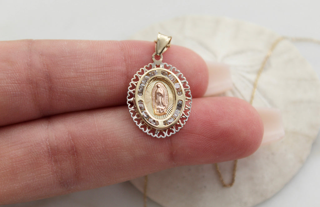 14K Gold Our Lady of Guadalupe necklace. The Guadalupe Pendant has a 14K Rose Gold guadalupe in the center, 14K Yellow Rays surrounding her, 4 curved lines in 14K Yellow Gold that make an cut oval with imbedded Cubic Zirconias, then the outer layer is 14K Gold White Hearts Frame. 