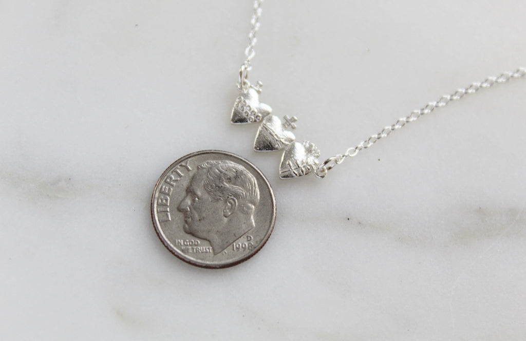 Holy Family Hearts Necklace in 925 Sterling Silver. Pendant size: 3/4" X 1/4". Pendant has all three hearts of the Holy family. Chain is a simple and dainty Link style. handmade in southern california. Pendant has hearts side by side: Sacred Heart, Immaculate Heart, Chaste Heart.