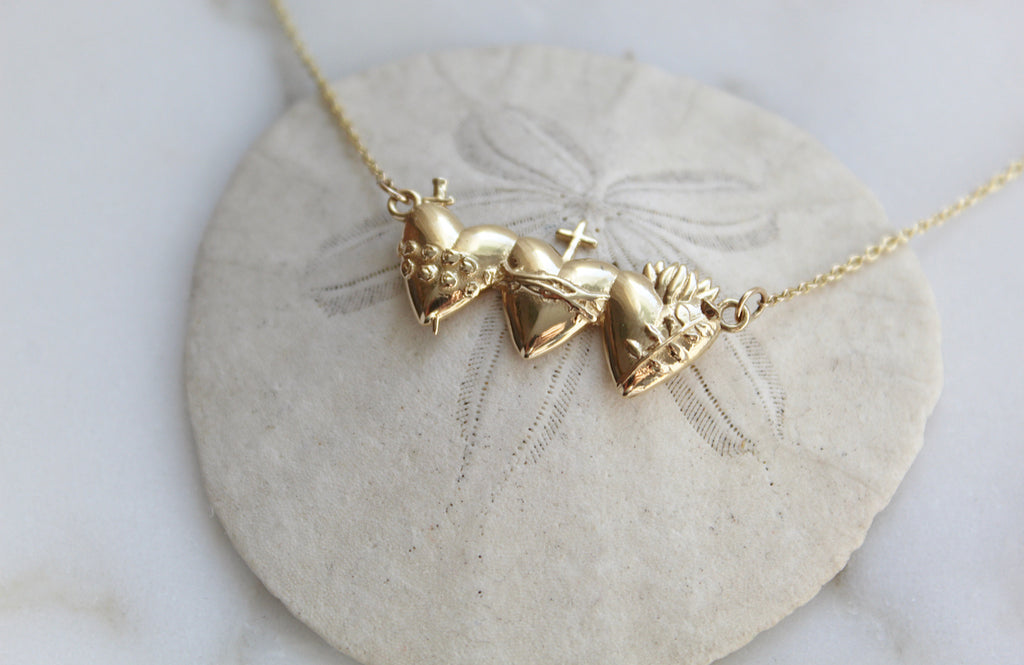 This is the Holy Family Hearts Necklace in Solid 14K Gold. This necklace has all three of the Sacred Hearts of the Holy Family. Jesus Sacred Heart, Immaculate Heart, & Chase Heart of Joseph. Ethically handmade in Southern California. Medal Size: 1" x 1/2"