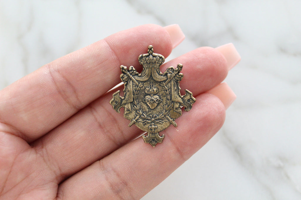 Sacred Heart Catholic Medal in the Shape of a Shield with a crown on top, two Swords, and is solid bronze.