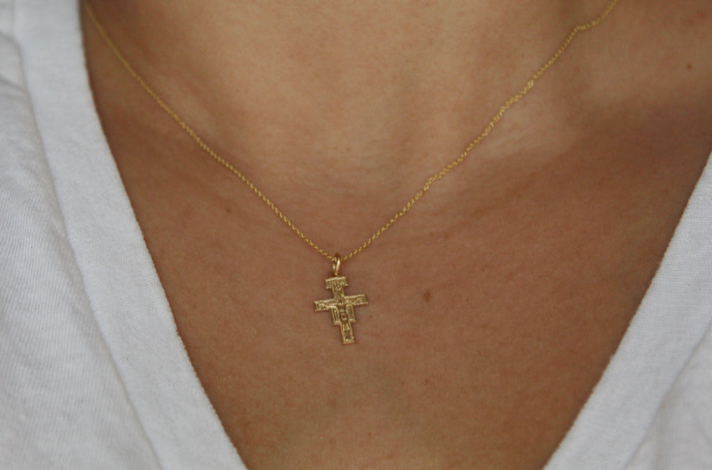 14K Gold San Damiano Crucifix necklace draped over models chest to show size. Size of Handmade 14K Gold Pendant on the 14K Gold Dainty Chain is 5/8"x3/8".