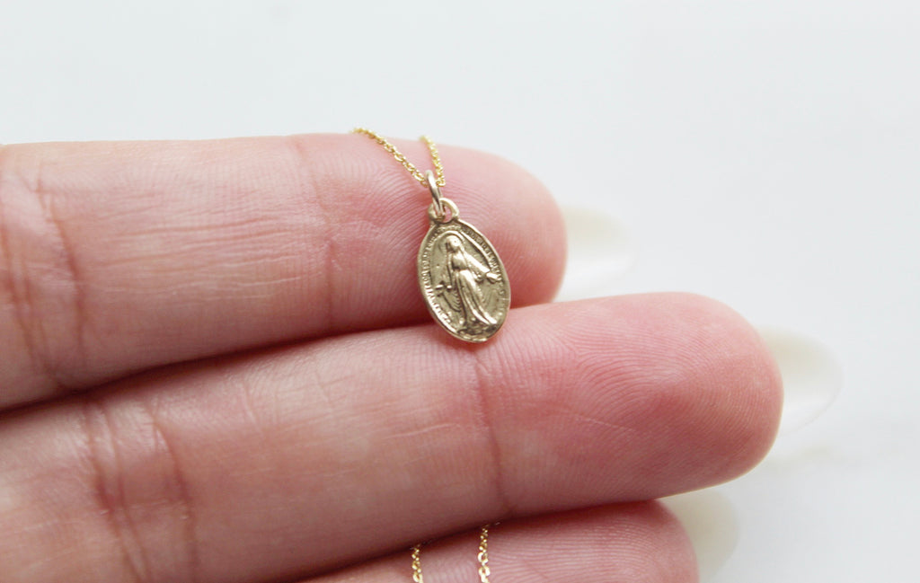 Handmade miraculous medal necklace in 14K Gold. Handmade Miraculous Medal is 1/2"x1/4". Chain is 14K Gold & dainty. This is a traditional miraculous medal with the Marian image on the front and Marian cross & 12 stars on the back.