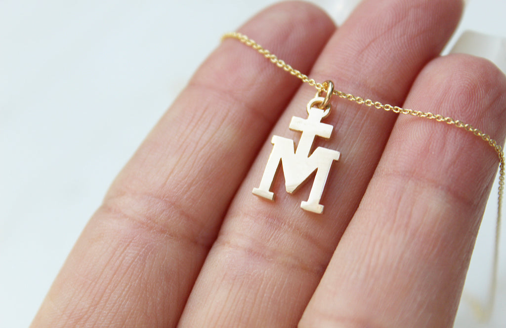 14K Gold Marian Cross necklace. Its a Cross Above the letter "m". The Marian Cross does not have any design on the front or back. It's just a "T" above the "M". The Chain on the necklace is dainty. Medal is 11/16"x7/16"