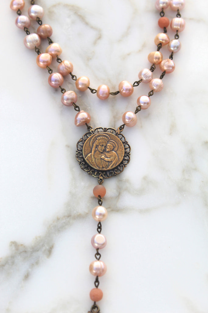 Gorgeous photo of the Pink Pearl rosary. The Rosary center has a ornate frame and a simple photo of jesus and mary.