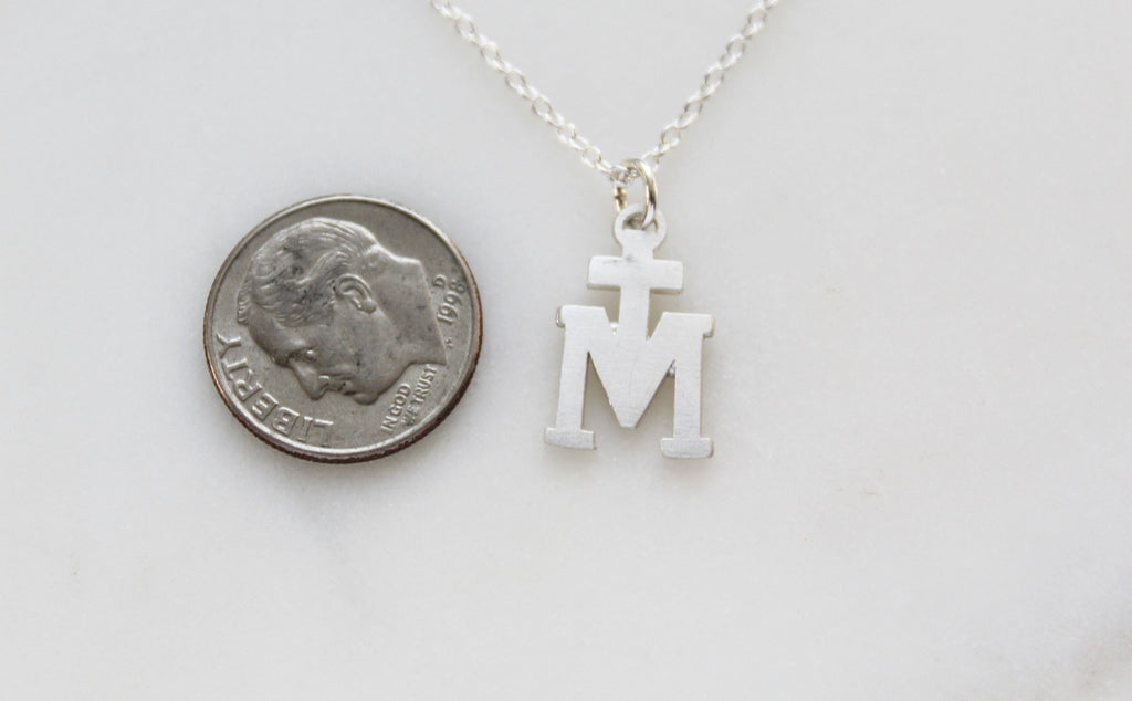 Sterling Silver Marian Cross necklace. Its a Cross Above the letter "m". The Marian Cross does not have any design on the front or back. It's just a "T" above the "M". The Chain on the necklace is dainty. Medal is 11/16"x7/16"