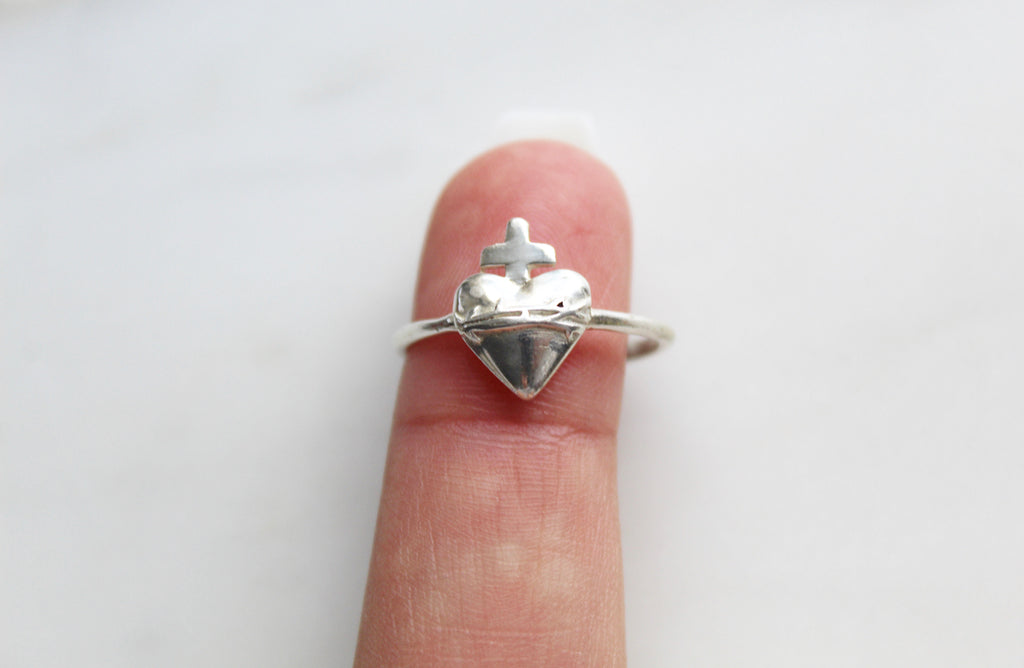 Sacred Heart of Jesus Ring in 925 Sterling Silver. The ring has a dainty simple band and the Sacred Heart of Jesus is on it. The heart design is raised and beautiful. Inside of the ring is blank. Ring is handmade in America.  Sacred Heart on Ring is  14.09mm x 11.22mm