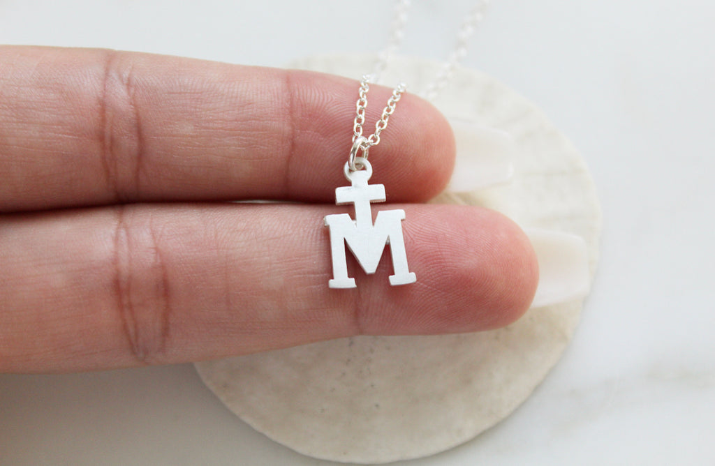 Sterling Silver Marian Cross necklace. Its a Cross Above the letter "m". The Marian Cross does not have any design on the front or back. It's just a "T" above the "M". The Chain on the necklace is dainty. Medal is 11/16"x7/16"