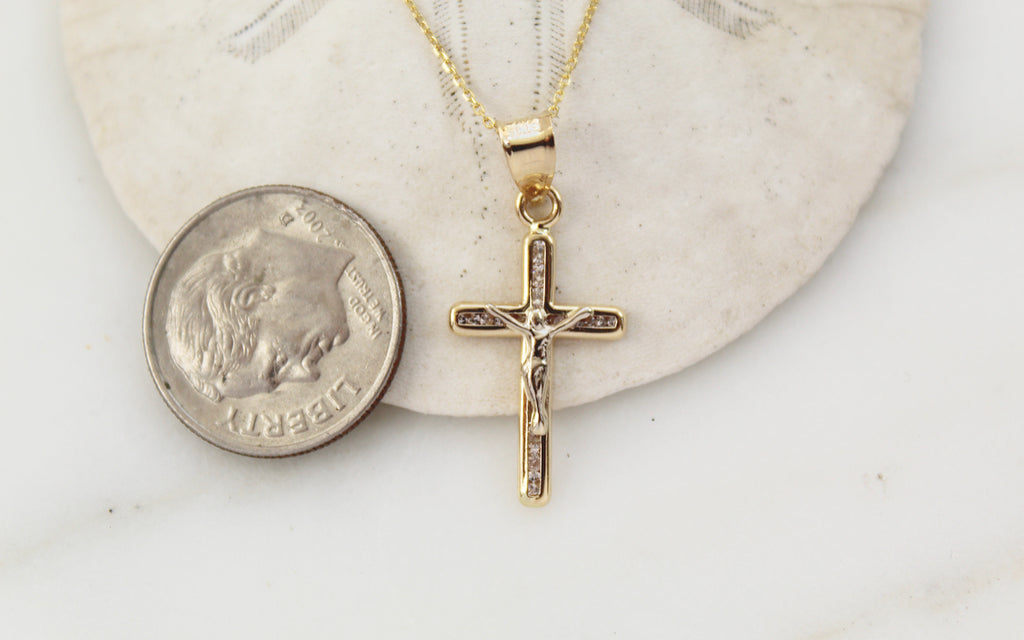 14K Gold Crucifix Pendant next to an American Dime to show the Size comparison. The Crucifix pendant is almost the same height as the dime from the top to the bottom go the crucifix.